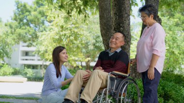 Tekerlekli sandalyedeki hastayla ilgilenen ve annesiyle konuşan bir kız. Bakıcının, birikimin, sağlık sigortasının, mutlu bir ailenin ve emekliliğin özenle mutlu emeklilik kavramı.