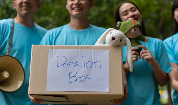 Happy young Asian students diverse volunteers hold donate box and toys for charity to share children and orphanages, a charity for sustainability. Volunteer work lifestyle and social cooperation
