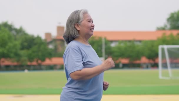 老年妇女在室外体育场慢跑 老年女性在夏天散步或跑步时 为有氧运动促进健康和健康而感到高兴 促进健康的保健和积极生活方式的概念 — 图库视频影像