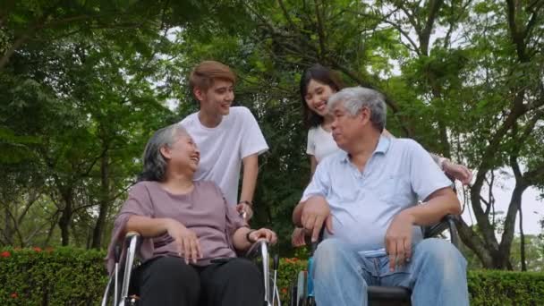 幸せな祖父母と孫のグループが一緒に話し おばあちゃんは車椅子に座っています 家族との退職生活 家族の良い世代の関係 シニアライブコンセプト — ストック動画