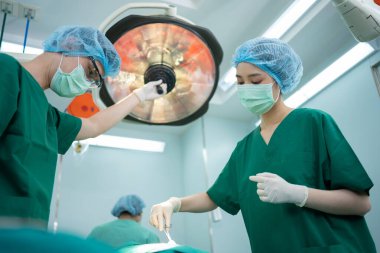 Asyalı Profesyonel Cerrahlar Ekibi ameliyathanede cerrah, asistan ve hemşireler Hasta, sağlık kanseri ve hastalık tedavisi konseptini ameliyat ediyorlar.