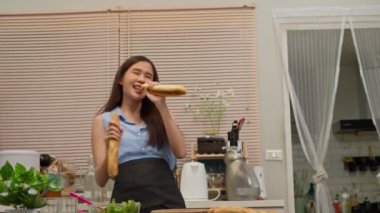 Mutfakta dans eden mutlu ve rahatlatıcı genç Asyalı kadın. Komik bayan ev hanımı müzik dinlerken eğleniyor sağlıklı bir sabah yemeği hazırlıyor, genç kadın kavramı evde tembellik haftasonunun keyfini çıkarıyor..