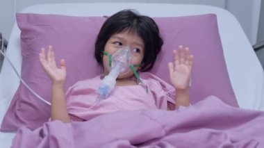 Küçük bir Asyalı kızın oksijen maskesi var ve hastanede nebulizatörle nefes alıyor. Bronşit konsepti, solunum ve tıbbi tedavi, nebulizatörden solunum ilacı, sis,.