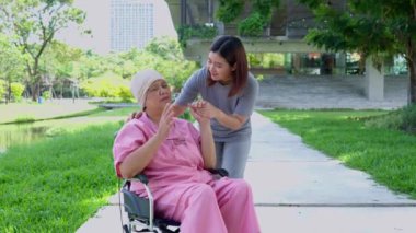 Asyalı dikkatli bakıcı ya da kanserli hemşire ve kadın tekerlekli sandalyede oturuyor. Bahçede. Bakıcının, birikimin ve sağlık sigortasının özenle mutlu emeklilik kavramı.