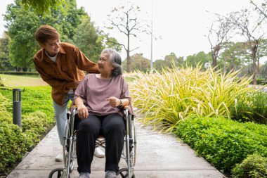 Tekerlekli sandalyedeki hastayla ilgilenen Asyalı dikkatli bir bakıcı ya da hemşire. Bakıcının, birikimin ve sağlık sigortasının özenle mutlu bir emeklilik kavramı. Mutlu bir aile.