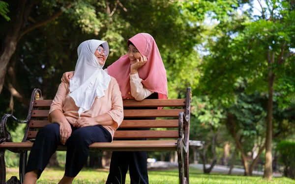 Hastane parkında hastayla ilgilenen Müslüman dikkatli bir bakıcı ya da hemşire. Mutlu Müslüman anne tesettüre sarılmış kız çocuğu. Tasarruf ve Kıdemli Sağlık Sigortası kavramı, Mutlu Bir Aile