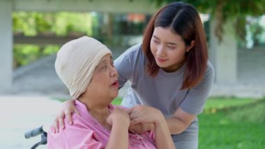 Asyalı dikkatli bakıcı ya da kanserli hemşire ve kadın tekerlekli sandalyede oturuyor. Bahçede. Bakıcının, birikimin ve sağlık sigortasının özenle mutlu emeklilik kavramı.