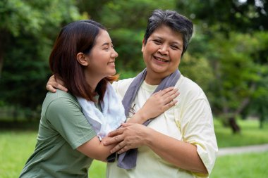 Parkta sabah egzersizinde birlikte çalışan çekici bir anne ve kız çocuğu. Kız konuşur, gülümser ve annesiyle güler. Üst düzey bir bakıcı ve mutlu bir aile kavramı..