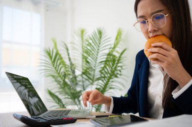 Meşgul ve yorgun iş kadını öğle yemeğinde ekmek ve süt yiyor ve patrona mali beyannameleri iletmek için çalışıyor. Hazır yemekler, tükeniş konsepti için çok çalışılmış ve sağlıksız..