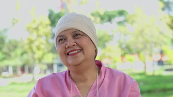亚洲老年妇女病人坐在公园花园的轮椅上 笑容满面 老年妇女从癌症检查中获得了良好的结果 并从癌症中恢复过来 — 图库视频影像