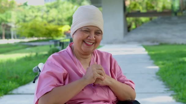 公園の庭で車椅子に座っているアジアの高齢女性の幸せな笑顔 年齢の女性はがん検査から良い結果を得て 病気から回復しました — ストック動画