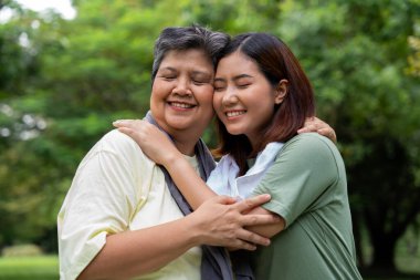 Parkta sabah egzersizinde birlikte çalışan çekici bir anne ve kız çocuğu. Kız konuşur, gülümser ve annesiyle güler. Üst düzey bir bakıcı ve mutlu bir aile kavramı..
