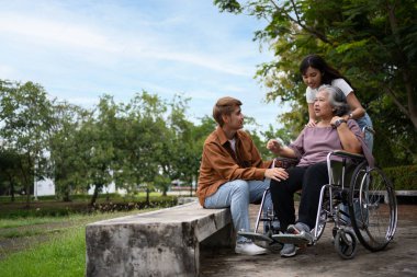 Tekerlekli sandalyedeki hastayla ilgilenen Asyalı dikkatli bir bakıcı ya da hemşire. Bakıcının, birikimin ve sağlık sigortasının özenle mutlu bir emeklilik kavramı. Mutlu bir aile.