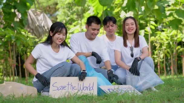 快乐的年轻亚洲学生们 各种各样的志愿者 在公园里举着一个清洁的活动标志 世界环保日 的理念 回收利用 慈善促进可持续性 — 图库视频影像