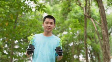 Mutlu Asyalı gönüllüler ellerinde bitki, ekoloji konsepti tutuyorlar. Erkek gönüllü, tohum ekiyor ve ağaçlar ekiyor. Bahçede büyüyüp Dünya 'yı kurtarmak için çalışıyorlar..