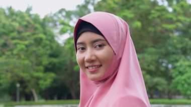 Açık havada gülümseyen türbanla kaplı neşeli genç bayanın yakın yüzü. Sıradan bir İslami kız parkta. Özgürlük ve dışarıda dinlenme. Mutluluk, gülümseme ve mutlu bir Müslüman kadın yüzü.