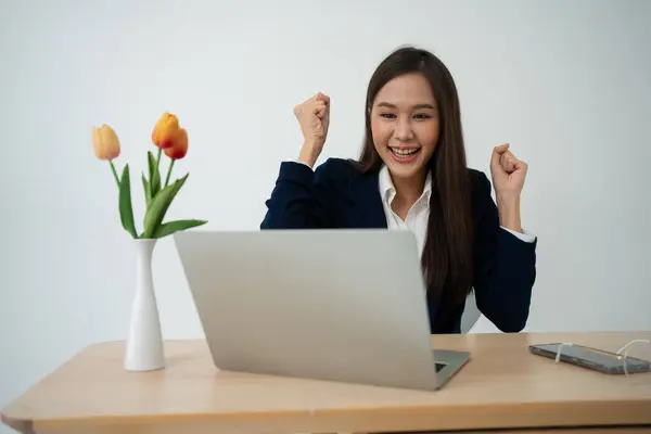 stock image Portrait of a Young attractive Asian woman in a black business suit feeling euphoric celebration online win success achievement result. Success, win, victory, triumph, congratulation, concept.