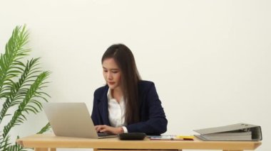 Modern ofis masasındaki gülümseyen güzel Asyalı kadının portresi çalışmak ve notlar yazmak için dizüstü bilgisayar kullanması, iş adamlarının online pazarlama e-pazarlama konsepti.