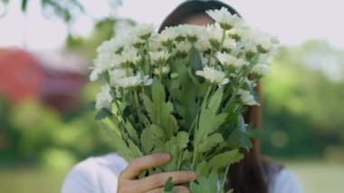Mutlu gülümseyen güzel Asyalı kadın yüzünde bir gülümsemeyle güpegündüz parktaki kameraya bakıyor, doğal güneş ışığı, Asyalı bir kızın portresi..