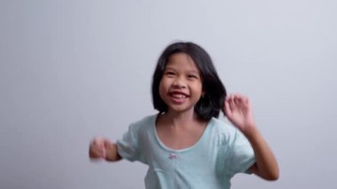 Küçük komik Asyalı kız kameraya bakıp yanaklarını işaret eden, çocukluk tanıklığı konseptinin tadını çıkaran, pozitif çocuk, 4k görüntü, Yavaş Hareket Portresi