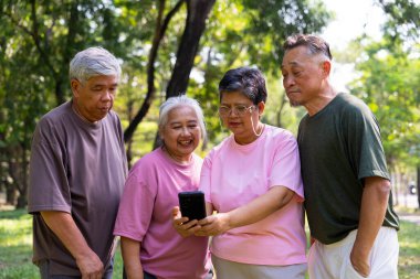 Bir grup mutlu kıdemli emeklinin akıllı telefon kullanması ve spor yaptıktan ve birlikte zaman geçirdikten sonra parkta kahkahalar atması, yaşlılarla, kıdemlilerle ve sağlık yaşlanmalarıyla ilgili kavramlar.