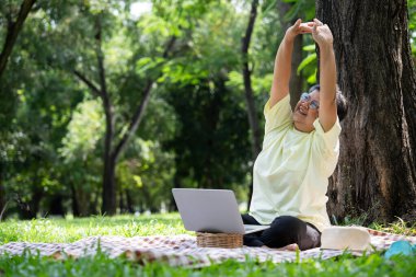 Mutlu Asyalı son sınıf öğrencisi ofis dışında çalışmak için dizüstü bilgisayar kullanıyor. Yaşlılar emekli olurken dizüstü bilgisayar kullanarak parkta çalışarak yeni beceri ve serbest çalışma, teknoloji ile yaşlılar yaşam tarzı öğreniyor.