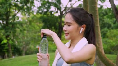 Egzersizden sonra şişeden su içen mutlu sağlıklı kadın. Spor, beslenme şişesi ve bayan sporcular egzersiz yaptıktan sonra sıvı içerler, sağlıklı ve aktif bir yaşam tarzı konsepti.