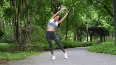Asyalı kadınlar parka koşmaya gitmeden önce kaslarını esnetiyorlar, gülümseyen spor yapan kadın esneme ve egzersiz yapıyor, sağlıklı bir yaşam tarzı, gülümseyen spor kadını.