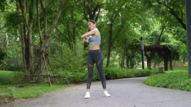 Asyalı kadınlar parka koşmaya gitmeden önce kaslarını esnetiyorlar, gülümseyen spor yapan kadın esneme ve egzersiz yapıyor, sağlıklı bir yaşam tarzı, gülümseyen spor kadını.