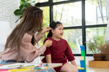 Kiraz rengi genç anne, Down sendromlu kızıyla renkli oyuncak bloğu oynar. Renkli tahta oyuncaklar, gelişimi arttırmak ve yavaş yavaş öğrenme becerilerini artırabilir.