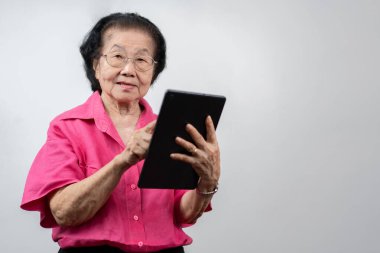 Kıdemli Kadın Sayısal Teknolojiyi Kucaklıyor: Tabletinde video sohbetleri yaparken sıcacık gülümseyen yaşlı bir Asyalı kadının portresi, tableti, eğitimi, çevrimiçi eğitim ve yaşlıların öğrenme faaliyetleriyle meşgul.