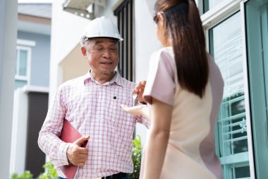 Mutlu Yeni Ev Sahibi: Gülümseyen bir mimar ya da müteahhit yeni evinin önünde mutlu bir genç kadına anahtarları verir.