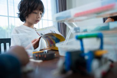 Genç Mühendisler: çok ırklı çocuklar, küçük robotik üretimi, merak göstergesi, takım çalışması ve erken STEM eğitimine odaklanmış durumdalar. Odaklanan robot ve çocuklar çarpışmaya hazırlanıyor..