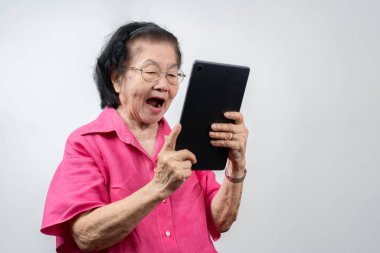 Kıdemli Kadın Sayısal Teknolojiyi Kucaklıyor: Tabletinde video sohbetleri yaparken sıcacık gülümseyen yaşlı bir Asyalı kadının portresi, tableti, eğitimi, çevrimiçi eğitim ve yaşlıların öğrenme faaliyetleriyle meşgul.