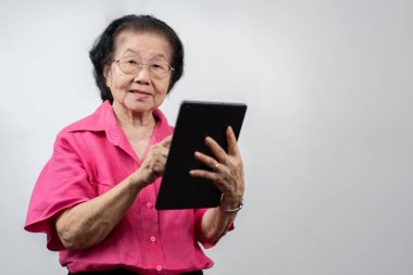 Kıdemli Kadın Sayısal Teknolojiyi Kucaklıyor: Tabletinde video sohbetleri yaparken sıcacık gülümseyen yaşlı bir Asyalı kadının portresi, tableti, eğitimi, çevrimiçi eğitim ve yaşlıların öğrenme faaliyetleriyle meşgul.