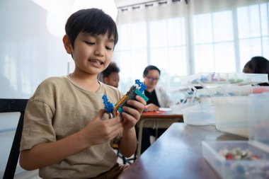 Genç Mühendisler: çok ırklı çocuklar, küçük robotik üretimi, merak göstergesi, takım çalışması ve erken STEM eğitimine odaklanmış durumdalar. Odaklanan robot ve çocuklar çarpışmaya hazırlanıyor..