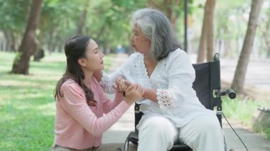 Tekerlekli sandalyedeki hastayla ilgilenen Asyalı dikkatli bir bakıcı ya da hemşire. Bakıcının, birikimin ve sağlık sigortasının özenle mutlu emeklilik kavramı. Mutlu bir aile.
