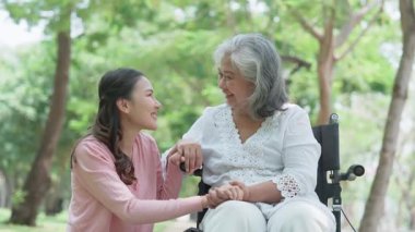 Tekerlekli sandalyedeki hastayla ilgilenen Asyalı dikkatli bir bakıcı ya da hemşire. Bakıcının, birikimin ve sağlık sigortasının özenle mutlu emeklilik kavramı. Mutlu bir aile.