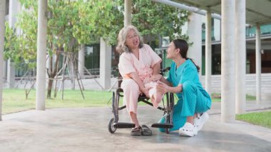 Tekerlekli sandalyedeki hastayla ilgilenen Asyalı dikkatli bir bakıcı ya da hemşire. Bakıcının, birikimin ve sağlık sigortasının özenle mutlu emeklilik kavramı. Mutlu bir aile.