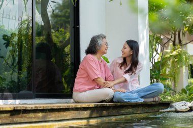 Kızları ve yaşlı anneleri, aile bağlarını güçlendirmek için samimi bir anı paylaşıyorlar. Bakıcı, sevgi ve destek sunuyor. İlişkilerini ve paylaşmanın güzelliğini vurguluyor.