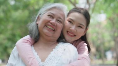 Gülümseyen bir kız, dışarıda annesine destek olur, neşeyi paylaşır ve aile bağlarını güçlendirir. İlişkileri derin bir özen ve duyguyu yansıtıyor. Emeklilik yolculuğunu sevgiyle kucaklıyor.