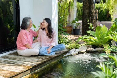 Kızları ve yaşlı anneleri, aile bağlarını güçlendirmek için samimi bir anı paylaşıyorlar. Bakıcı, sevgi ve destek sunuyor. İlişkilerini ve paylaşmanın güzelliğini vurguluyor.