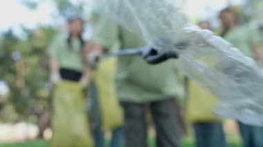 Toplum gönüllüleri parkta toplanıyor, doğayı temizlemek ve iyileştirmek için birlikte çalışıyorlar. Takım çalışmaları ve yardım çabaları sosyal sorumluluğu, çevreyi ve genel olarak refahı geliştirmeyi teşvik ediyor.