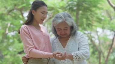 Gülümseyen bir kız, dışarıda annesine destek olur, neşeyi paylaşır ve aile bağlarını güçlendirir. İlişkileri derin bir özen ve duyguyu yansıtıyor. Emeklilik yolculuğunu sevgiyle kucaklıyor.