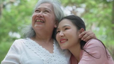 Gülümseyen bir kız, dışarıda annesine destek olur, neşeyi paylaşır ve aile bağlarını güçlendirir. İlişkileri derin bir özen ve duyguyu yansıtıyor. Emeklilik yolculuğunu sevgiyle kucaklıyor.