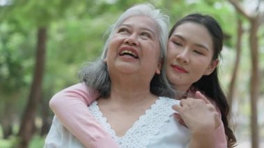 Gülümseyen bir kız, dışarıda annesine destek olur, neşeyi paylaşır ve aile bağlarını güçlendirir. İlişkileri derin bir özen ve duyguyu yansıtıyor. Emeklilik yolculuğunu sevgiyle kucaklıyor.