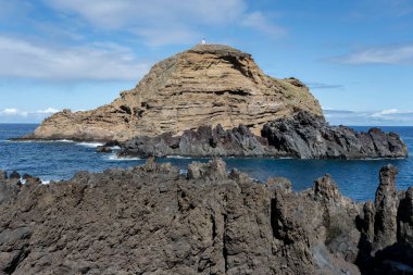 Portekiz, Porto Moniz 'de parlak sonbahar ışığı altında çekilen volkanik kayalıklarla Madeira adasındaki okyanus manzarası.