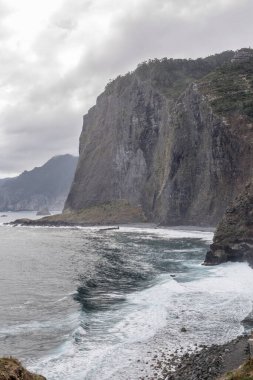 Fortim de Faial 'ın doğusunda Atlantik Okyanusu kıyısındaki dik yamaçlı manzara, Portekiz, Madeira' da açık bulutlu bir sonbahar ışığı altında çekilmiştir.