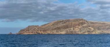 Porto Santo Adası 'ndaki Da Patacha pelerininin volkanik kayalıkları parlak sonbahar ışığı altında güneyden çekilen manzara.