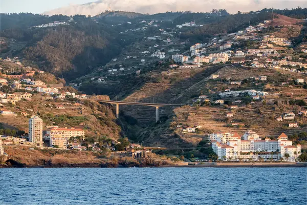 bridges and urban sprawl on green ocean shore at Madeira island, shot in bright dawn fall light east of Funchal, Portugal